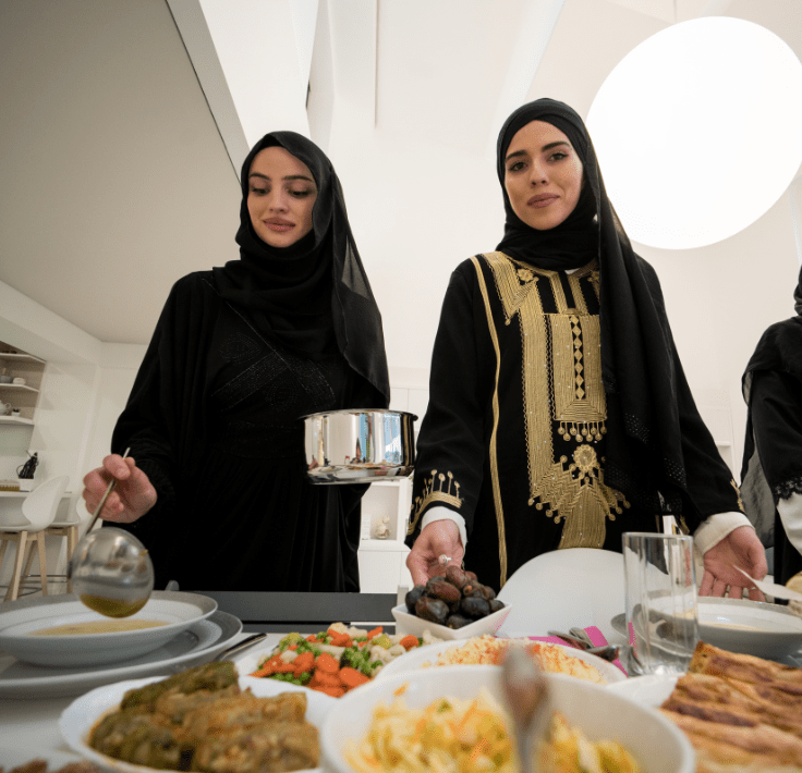 Two Muslim women preparing and serving food to break the fast during Ramadan